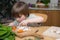Left-Handed Boy Cutting Carrot on a Wooden Board Very Carefully in the Kitchen