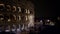 Left to right real time pan shot of night traffic nearby the Colosseo in Rome. The Colosseum also known as the Flavian