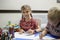 Lefty girl and righty boy writing at same desk and nudge each other with elbows, left-hander day