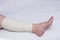 Leg of an elderly woman bandaged with an elastic bandage against varicose veins on the leg, close-up, white background