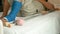 Leg on male patient with splint cast and crutches lying on hospital bed with pink piggy bank beside, saving money for health and