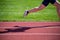 Leg and shadow of runner racing on athletic field with grass background