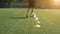 Leg skill training on football field. Soccer player running in football field leading ball between cones