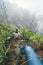 Leg of traveler staying on the ledge above the foggy green valley overgrown with agaves Santo Antao island in Cabo Verde