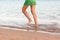 Leg of woman running on beach with water splashing. summer vacation. legs of a girl walking in water on sunset
