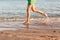 Leg of woman running on beach with water splashing. summer vacation. legs of a girl walking in water on sunset