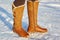Leg woman winter brown fur boots walking on the snow in a winter park. Closeup outsole of warm boot.