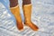 Leg woman winter brown fur boots walking on the snow in a winter park. Closeup outsole of warm boot.