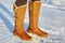 Leg woman winter brown fur boots walking on the snow in a winter park. Closeup outsole of warm boot.