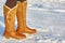 Leg woman winter brown fur boots walking on the snow in a winter park. Closeup outsole of warm boot.