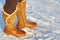 Leg woman winter brown fur boots walking on the snow in a winter park. Closeup outsole of warm boot.