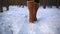 Leg woman winter brown fur boots walking on the snow in a winter park. Closeup outsole of warm boot.