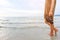 Leg of young woman walking along wave of sea water and sand on the beach in tropical island with carefree and relaxing attitude.