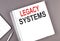 LEGACY SYSTEMS text on the notebook with calculator and pen