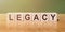 Legacy word from wooden blocks with letters on a green-brown background