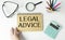 Legal Advice message on notebook with glasses, pencil and coffee cup on wooden table