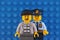 Lego criminal minifigure and policeman minifigure that standing behind criminal. Blue baseplate background