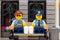 Lego policeman and policewoman minifigures sitting on a bench and drinking coffee and eating donuts