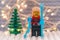 Lego skier minifigure with skis against Christmas tree and christmas light