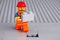 Lego worker minifigure with gray brick finishing building wall