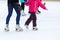 legs of an adult and child skating on the ice rink