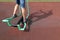 Legs of amateur athlete on street exercise machine, with shadow on the surface of the sports ground
