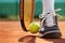 Legs of athlete near the tennis racket and ball