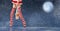 Legs of a ballerina on pointe shoes in striped golfs of Santa Claus walks against the backdrop of a night snowy sky and the moon