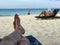 Legs on a beachchair and blurry man reading a book on the beach