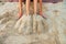 Legs beautiful young woman buried in sand on beach. woman sitting on sand