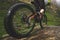 Legs of bicyclist and rear wheel close-up view of back mtb bike in mountains against background of rocks in foggy