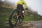 Legs of bicyclist and rear wheel close-up view of back mtb bike in mountains against background of rocks in foggy