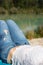 Legs with blue jeans of a girl which is spending her free time on the pebble beach