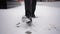 Legs Businessman in Black Shoes. Lonely Man Walks along a Snowy City Street