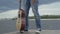 Legs of Caucasian man tapping rhythm on embankment. Unrecognizable musician with guitar standing on river bank listening