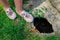 Legs of a child girl at a dangerous pit of failed asphalt in the yard near a sewer manhole. Background