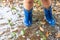 Legs of child wearing pair of blue rubber boots in water puddle