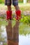 Legs of child wearing pair of red rubber boots with reflection i
