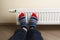 Legs with colorful socks in front of heating radiator