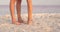 Legs of a couple walking on the beach at sunset. The camera captures only the legs of a couple walking along the beach