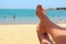 Legs covered by sand of girl sunbathing under sunshade. Enjoying summer vacations