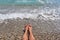 Legs of a girl on a pebbly beach