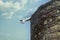 Legs of girl with pretty shoes stick off of top of rounded castle wall into air with pretty turqoise sky behind