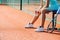 Legs of a girl sitting on a chair bench next to tennis court to take short break