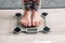 Legs of a girl standing on scale to measure weight. Caucasian female bare feet with weight scale at home. Person