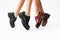 legs of girls in leather shoes red and black on a white background. fashion shoe collection autumn winter 21/22