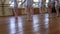 Legs of girls standing in third position during ballet lesson in frayed classroom.