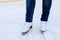 Legs of ice skater with white leather skates on ice rink, close up view