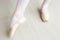 Legs of little balerina wearing pail pink pointe shoes with ribbons