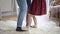 Legs of little girl stepping on man's feet and dancing. Unrecognizable Caucasian daughter dance with father indoors at
